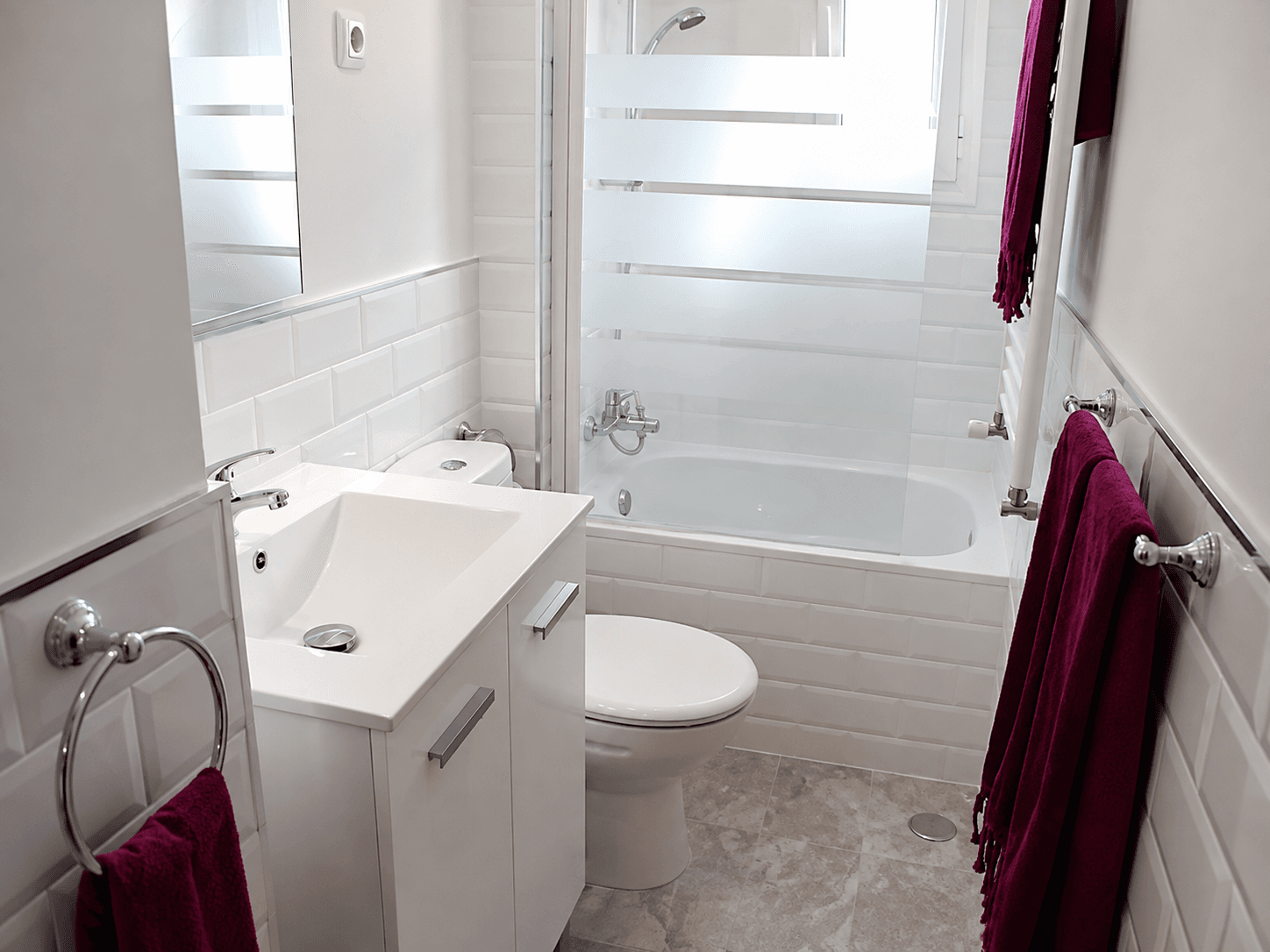 Baño después de la reforma, con alicatado blanco, mueble de lavabo y bañera nueva