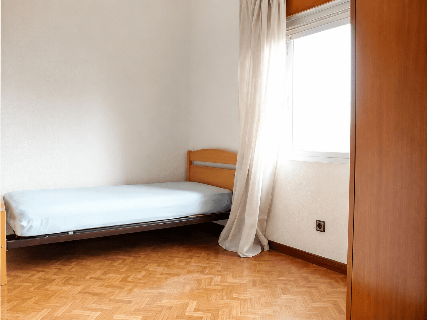 Dormitorio individual antes de la reforma, con suelo de parqué antiguo